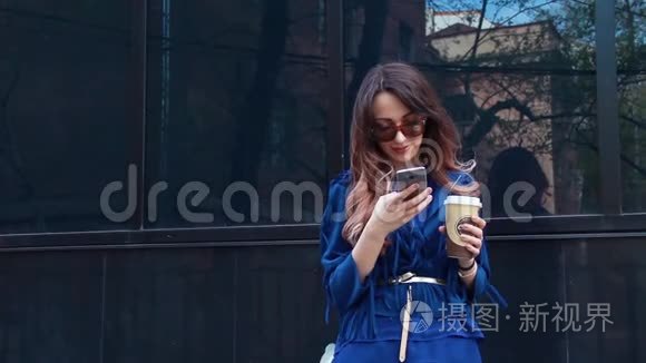 站在街上拿着智能手机和咖啡的漂亮女孩