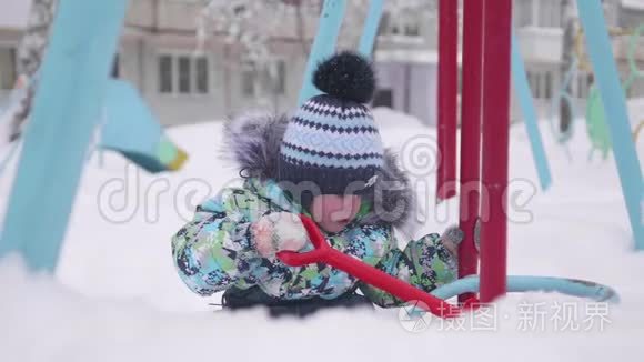 一个小孩在冬天的公园里玩雪.. 孩子拿着铲子，公园里有很多雪。 有趣的游戏