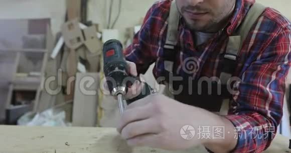 一个年轻的木匠用螺丝刀在家具生产中转动自攻。