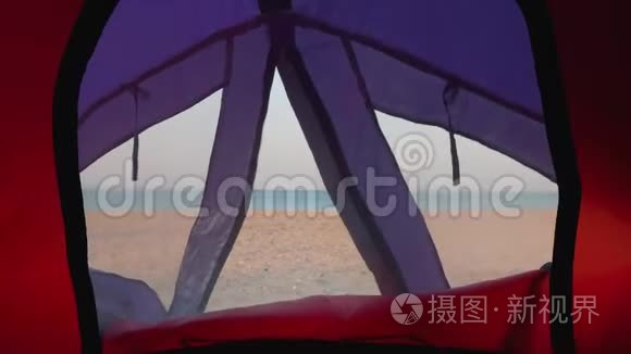 从帐篷里的小窗户看到荒芜的海滩和蓝色的大海