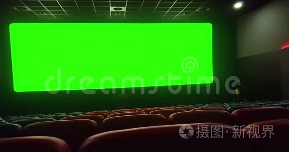 电影院内部有空的红色座位，色度键绿色屏幕和边缘发光，放大