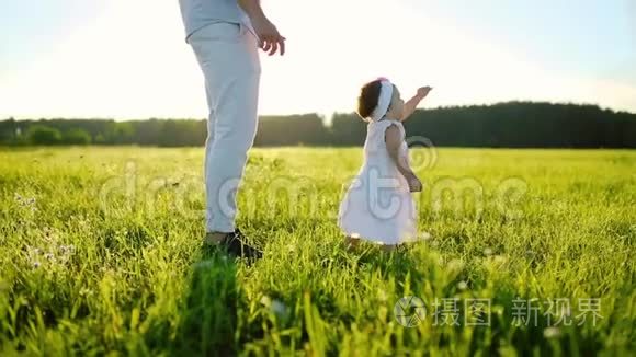 一家人在公园散步，小女儿迈出了第一步。 全都穿着白色的衣服，在夕阳下。