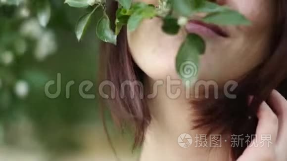 公园里一棵开花树附近的美丽女孩肖像。 青春和自然美的概念.. 一个年轻的女孩