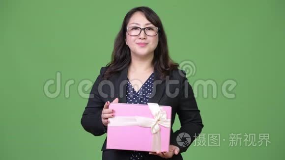 成熟美丽的亚洲女商人拿着礼品盒思考