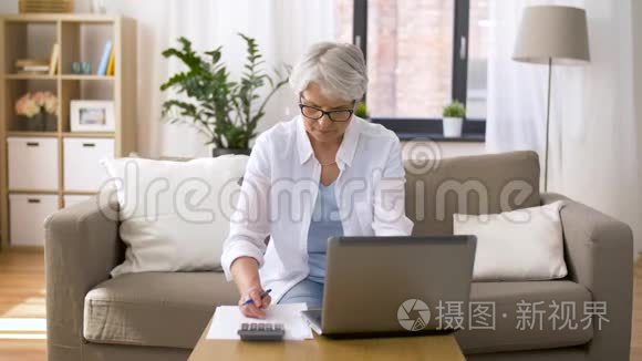 家里有笔记本电脑和计算器的老妇人