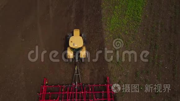 空中无人机跟踪拍摄拖拉机播种，在田间播种农作物。 从上面看