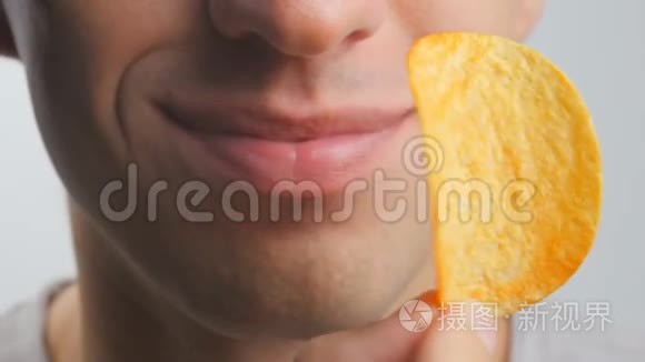 一个年轻人在白色背景下愉快地吃薯片的特写镜头