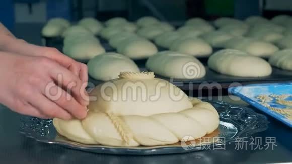 贝克正在用一块面团装饰一块圆面包，把它合上