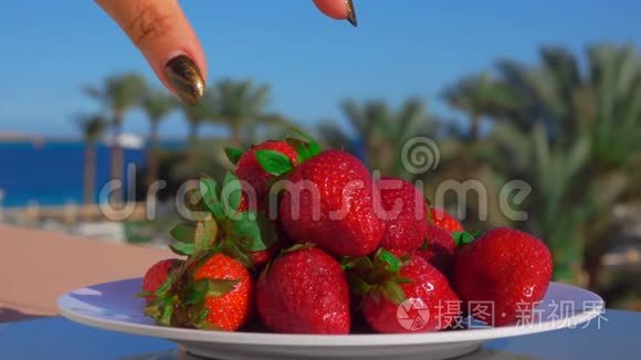 手从盘子里取出一大块多汁的草莓