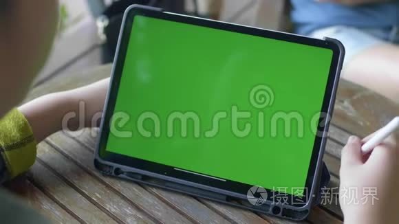 男孩在平板电脑上看绿色屏幕色度键。