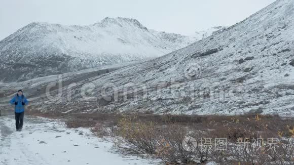 一个背着背包的人正沿着山间的一条雪道走着..