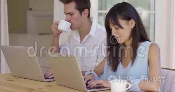 冷静的年轻夫妇坐在桌子上用笔记本电脑