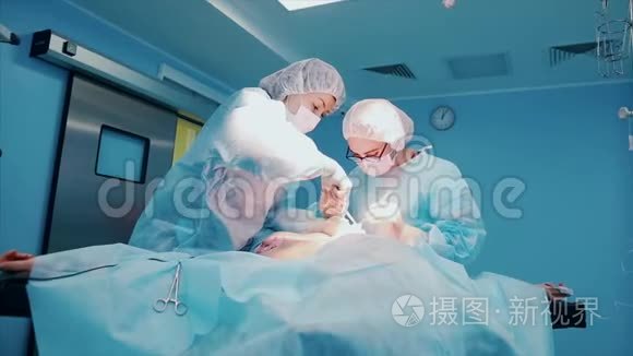 一组专业外科医生对医院手术室的一名病人进行侵入性手术。 外科医生使用和