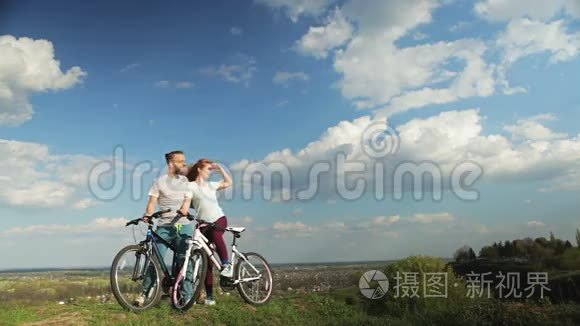 一对骑自行车的情侣站在高山上。