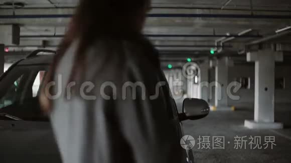 年轻的商务女性走到车辆对面的停车场，坐在车里。 女司机开车。