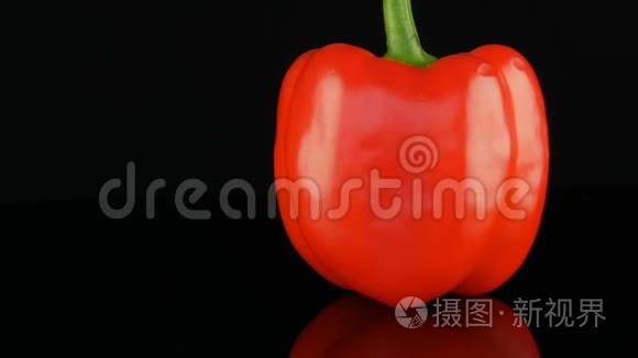 美丽的大熟红色甜椒辣椒在镜面和黑色背景上旋转。