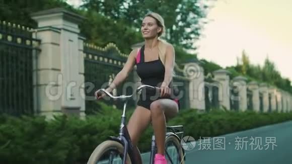 快乐的女人在城市公园骑自行车。 夏季自行车健身女孩训练