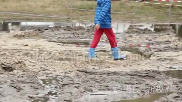 穿靴子的孩子走在泥坑上，孩子们不安全的照顾