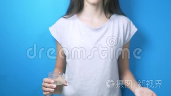 保健概念。 特写镜头。 女孩拿着一杯水和药丸。