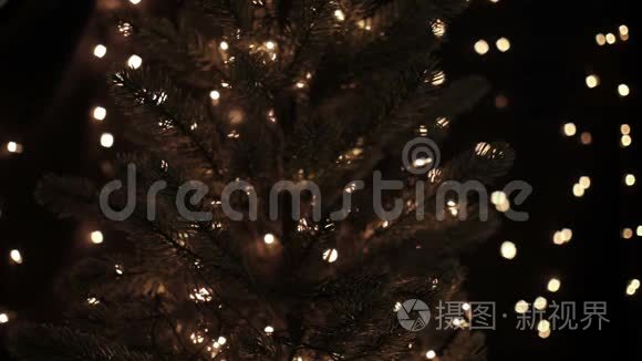 女人在圣诞树上装饰着星星花环，背景是闪闪发光的灯光