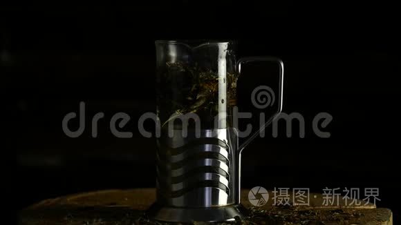 把热水茶叶倒在玻璃茶壶里，背景很黑。 慢动作