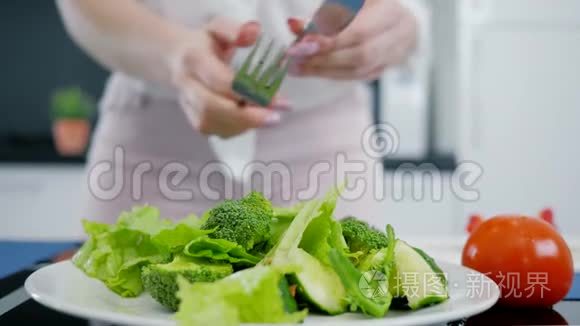 生菜和西兰花和黄瓜，手在厨房里混合新鲜的有机绿色沙拉