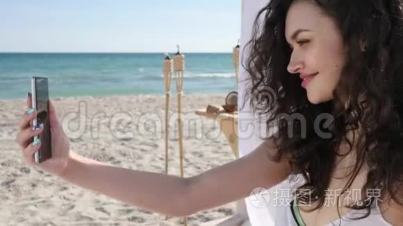 沙滩上的年轻女子，手机删除节日照片，微笑的女孩在背景海洋上自拍