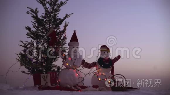 带圣诞礼物的雪人。 两个雪人站在冬天的圣诞节风景