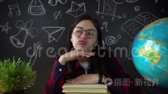 在学校艺术课上做一个项目的微笑少女画像。 女生坐在学校的办公桌前。