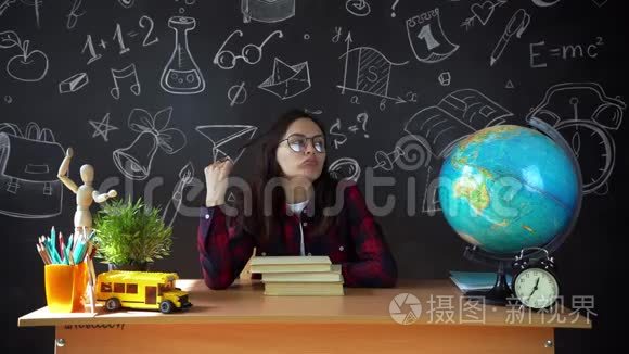 在学校艺术课上做一个项目的微笑少女画像。 女生坐在学校的办公桌前。