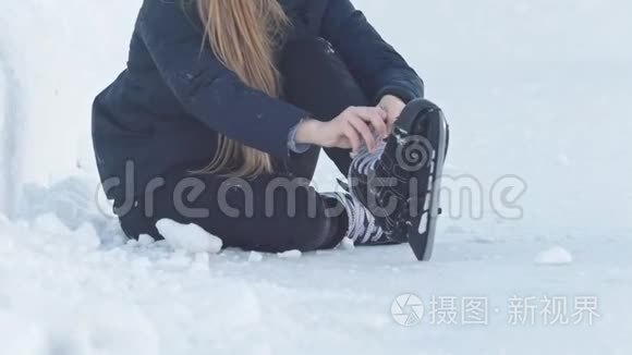 坐在雪地上收紧溜冰鞋带的少女