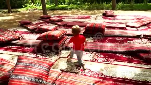 有趣的小男孩在公园里用地毯和床垫奔跑和欢乐。
