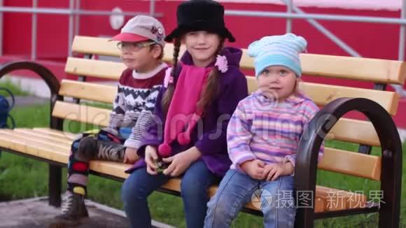 三个快乐的孩子坐在木凳上挥手视频