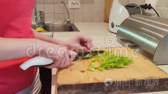 特写镜头。 女人在家里厨房的木板上切绿色的辣椒
