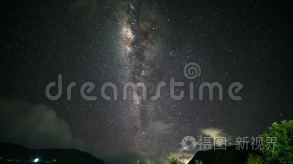 夜晚的风景随着五颜六色的银河和多云的光线在山上流逝。 带热带山脉的星空