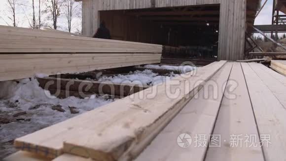 在锯木厂院子里存放的一堆堆积的木材上工作的人