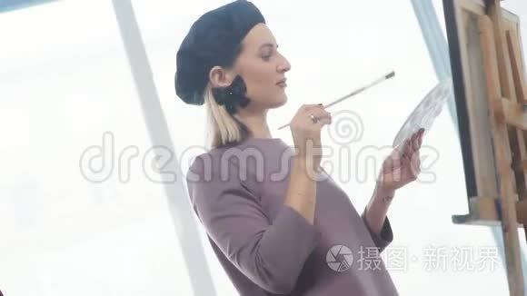 女艺术家在贝雷帽里，拿着画笔，微笑着