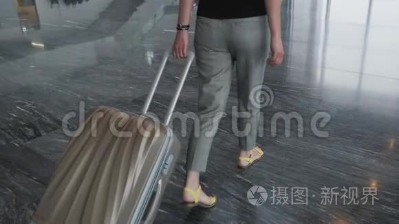 年轻漂亮的商务女性在机场边走边带着行李等待登记、旅行