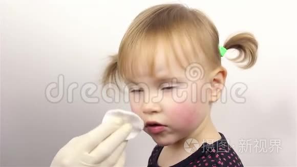 皮肤护理。 一个漂亮的小女孩的肖像，妈妈把保湿霜放在脸上。