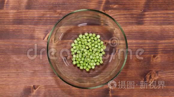 豌豆慢慢地在桌子上装满了一个玻璃碗