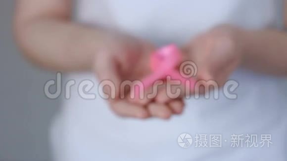 女士双手捧着粉红色乳腺癌意识丝带-乳腺癌意识概念