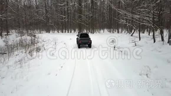 越野车6x6在冬季森林中的雪覆盖道路上行驶，后视