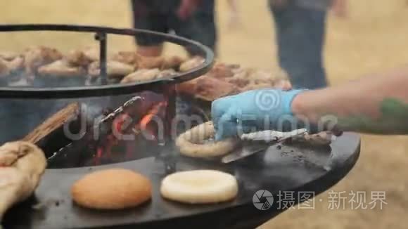 厨师用锅铲在烤架上为汉堡翻包子和香肠