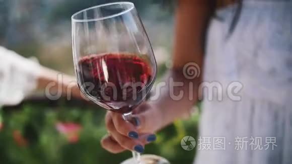 年轻女子的手在户外摇着一杯红酒