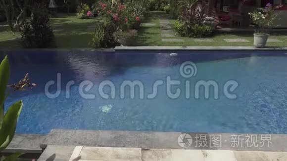 印度尼西亚巴厘岛，阳光明媚的一天，在蓝天的背景下观赏一个有游泳池和山脉的热带花园