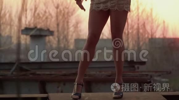 优雅的女人在金属建筑的夕阳下翩翩起舞