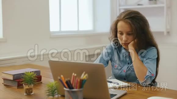 带手提电脑的年轻女孩正在做作业。 大学教育。 在家学习和使用电脑的女生