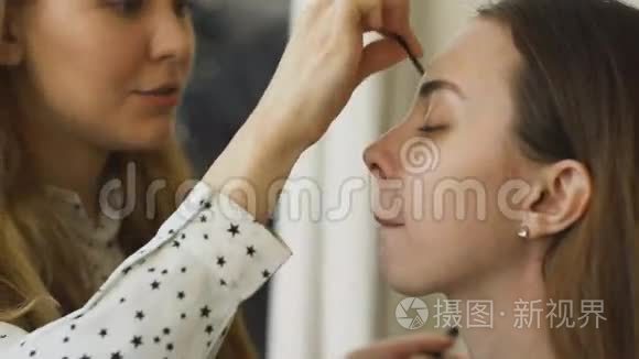 年轻的化妆师在一个重要的活动前为女孩做漂亮的眉毛特写化妆