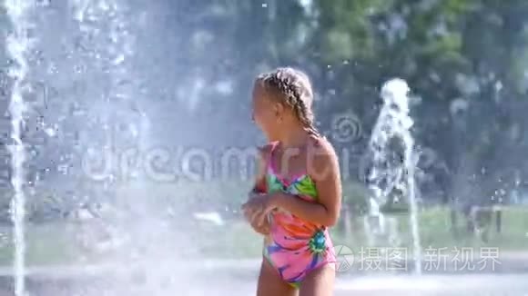 七岁的快乐女孩，穿着泳衣，在喷水池里嬉戏。 城市里阳光明媚的夏日