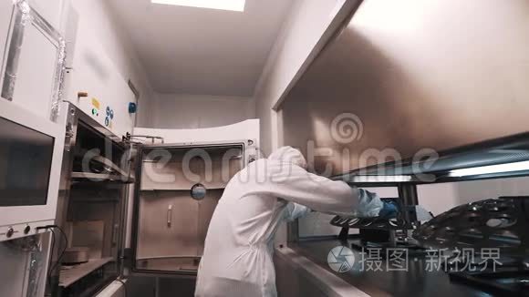 穿着长袍和橡胶手套的工程师在实验室将金属元素放入烤箱